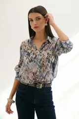 Camisa celeste con estampado abstracto en tonos marrones y azules, de corte clásico, cuello camisero y mangas largas con puños abotonados.