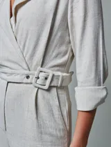 Mono largo color crudo, de lino, con cuello tipo blazer, mangas 3/4 con puños arremangados, cinturón con hebilla forrada y pantalón de corte recto.