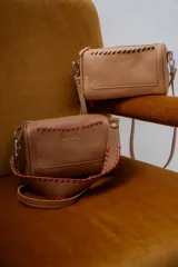 Cartera de cuero color beige con doble correa, una de cuero fina y otra ancha con trenzado en contraste de color verde.