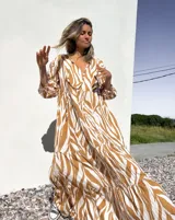 Vestido largo tipo túnica con estampado de cebra en tonos beige y crudo, con cuello en V y mangas 3/4.