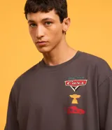 Remera gris de corte boxy, con cuello redondo y mangas cortas. Estampado frontal con logo de la película Cars, una copa y un auto.