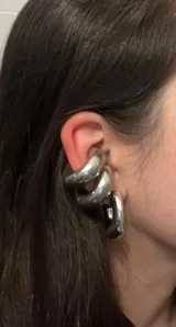 Aros tipo cuff plateados, gruesos y de diseño moderno.
