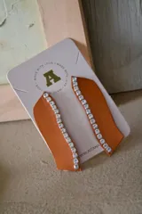 Aros colgantes color naranja con una línea de strass plateado. Cierre de gancho.