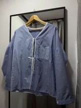 Camisa celeste y azul a rayas verticales con cuello en V y lazos blancos para atar en el frente.