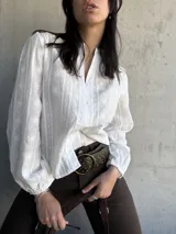 Camisa blanca con bordado floral, cuello mao y mangas largas abullonadas.