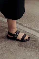 Sandalias doradas de cuero, con dos tiras anchas sobre el empeine y tobillo con hebilla lateral ajustable.