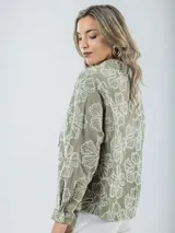 Blusa color crudo con bordados florales, cuello camisero y mangas largas.