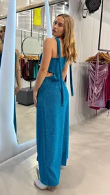 Vestido largo de fiesta color turquesa brillante, con escote asimétrico, abertura lateral y corte en la cintura.