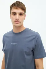 Remera azul con estampado de conchas marinas en la espalda y logo de la marca en la parte superior.