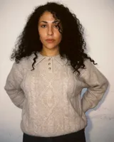 Sweater color beige tejido en lana simil cashmere, con cuello polo y cartera abotonada.