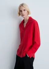 Camisa roja de tejido fluido con cuello camisero, cierre frontal con botones, manga larga y puños abotonados.