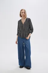 Camisa holgada de viscosa con estampado de rayas verticales en blanco y negro, cuello en V y mangas 3/4 con detalle de botones.