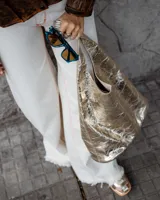 Bolso de hombro negro de cuero con apliques metálicos plateados.