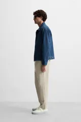 Pantalón slim fit negro confeccionado en tejido con elasticidad en ambas direcciones. Cuenta con bolsillos frontales y traseros de vivo con botón. Cierre frontal con cremallera y botón.
