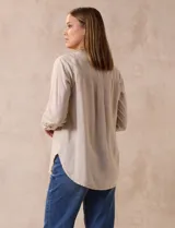 Blusa beige de lino y rayón, marca Dash. Tiene cuello a la base, escote en V y abertura con botones. Delantera con bolsillos. Largo de manga regulable con presilla y botón.