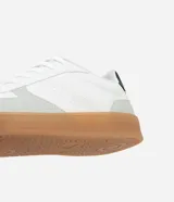 Championes urbanos de corte bajo, color blanco con detalles en gris y negro. Confeccionados en material sintético con recortes efecto gamuza y suela de látex color caramelo.