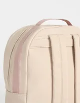Mochila color beige de tela deportiva con textura. Tiene correa regulable, manija superior, cierre superior, doble bolsillo frontal con cierre y pullers, y bolsillos laterales.