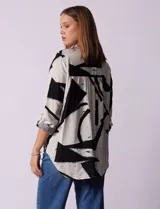 Camisa de manga larga con estampado abstracto en tonos verde y blanco. Cuello con solapa y abertura central con botones. Largo de manga regulable con presilla y botón. Terminación de ruedo anudada opcional.