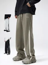 Pantalón deportivo estilo jogging, color verde oliva, con cintura ajustable con cordón y bolsillos laterales. Presenta una franja lateral doble en color blanco.