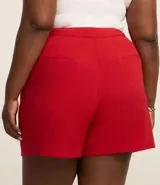 Bermuda roja de crepé con cierre delantero, bolsillos laterales con botones y pliegues.