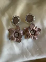 Par de aros colgantes con base circular negra con borde de strass y dije de flor negra con centro de strass.