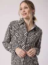 Camisa de manga larga con estampado de cebra en tonos beige, marrón y lila. Tiene cuello clásico, cierre con botones y un bolsillo en el pecho.