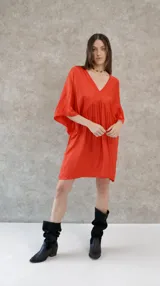 Vestido corto color beige, de raso, con escote en V y mangas 3/4. Corte holgado.