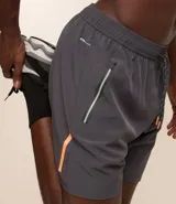 Bermuda deportiva negra sin estampado, con cintura elástica ajustable con cordón, y bolsillo lateral con cierre de cremallera contrastante.
