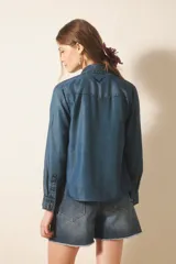 Camisa de manga larga confeccionada en tencel, color azul denim, de corte clásico, con cuello camisero, bolsillos en el frente y botones metálicos.