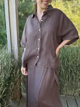 Camisa marrón de lino con botones blancos, corte holgado y mangas cortas.