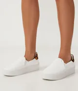 Championes slip on blancos de caña baja, sin cordones, con suela de plataforma y detalle de animal print de jaguar en el talón.