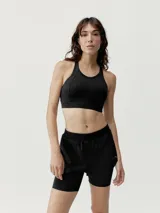 Top deportivo negro de alta sujeción, con corte atlético y pieza en curva para ajuste perfecto. Interior de tejido mesh para mayor ligereza y copas extraíbles.