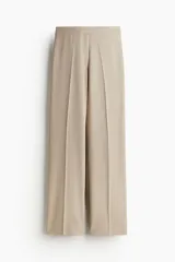Pantalón de vestir color beige, de tiro alto, corte ancho y pierna recta con pliegues.
