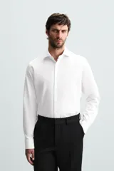 Camisa blanca de manga larga con cuello italiano abierto y puños abotonados. Presenta un corte slim fit y cierre frontal de botonadura.