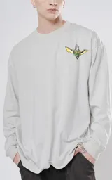 Remera de manga larga color gris claro, corte oversize y hombros caídos. Estampa pequeña en el pecho con la cara de un Gremlin.