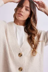 Cardigan de punto color crema, con escote en V, cierre frontal con botones marrones y corte holgado.