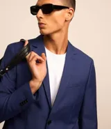 Saco de traje azul cobalto, modelo social, con cuello solapa, abotonado delantero, bolsillos y mangas largas.