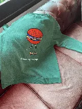 Buzo verde con estampa de una hamburguesa andando en skate y la frase "skateboarding hamburger".
