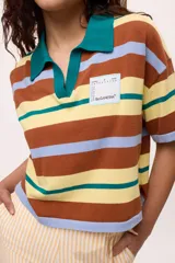 Remera tejida con rayas horizontales marrones, rosas y turquesas, cuello polo y calce boxy.
