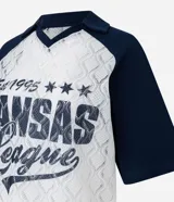 Remera de encaje blanco con mangas cortas raglán azul marino, cuello en V y estampado frontal con la inscripción "Kansas League Est. 1995".