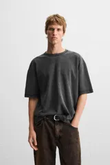 Camiseta color gris verdoso de punto tejido en hilatura de algodón, con cuello redondo, manga corta, efecto lavado y acabados irregulares.