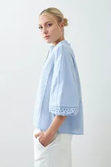 Blusa celeste con escote en V y bordado floral en el frente y en las mangas 3/4.