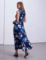 Vestido largo de seda fría con estampado floral en tonos azules y blancos, escote en V cruzado y cintura con faja plisada.