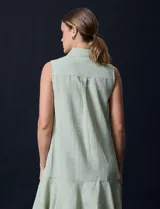 Vestido corto blanco de gasa, sin mangas, con cuello camisero, abertura central con botones y terminación de ruedo con volado.