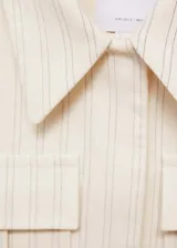 Chaqueta corta color crema con rayas verticales finas, cuello camisero, cierre frontal con botones ocultos, manga larga y dos bolsillos de parche en la parte delantera.