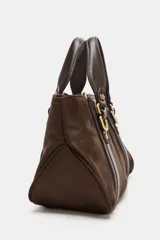 Bolso de mano tipo mini shopper en color marrón oscuro, confeccionado en material tipo gamuza o nobuk, con detalles de cuero liso en las asas y tiras laterales. Presenta herrajes metálicos dorados con forma de doble 'C' o anillo.