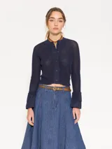 Cardigan azul marino de tejido de lino y algodón, largo hasta la primera cadera. Tiene mangas largas con puños acampanados de tela plana y cierre frontal con botones.