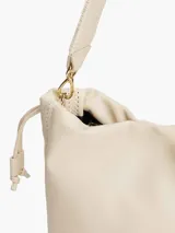 Cartera bombonera color crema con correa de hombro y cierre con cordón ajustable.