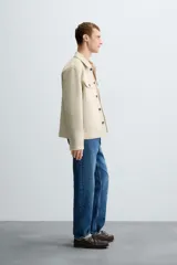 Sobrecamisa color beige de tejido efecto ante, corte regular fit, con cuello solapa, manga larga con puños abotonados, bolsillos de parche con solapa en el pecho y bolsillos de ojal en la cadera.