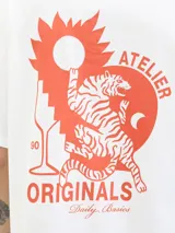 Remera blanca de algodón con cuello redondo y manga corta. Estampado en la espalda con un tigre, un sol y texto en color naranja.